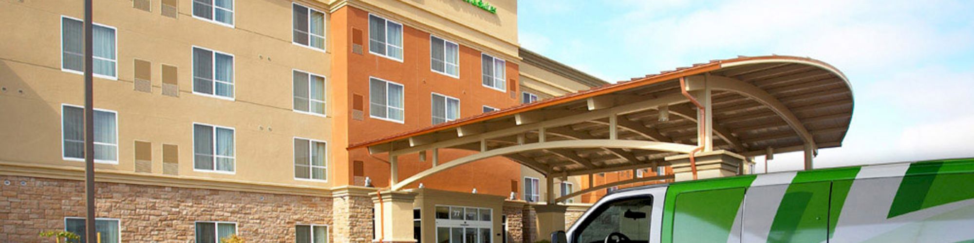 The image shows the entrance of a Holiday Inn Express hotel with its branded sign, and a green and white van parked in the foreground ending the sentence.