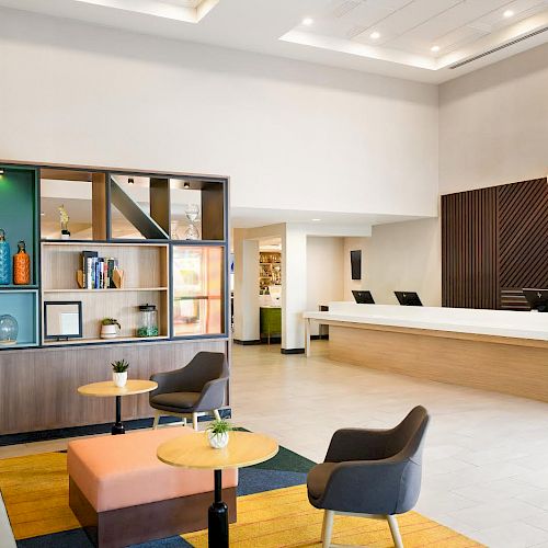 The image depicts a modern hotel lobby with a reception desk, contemporary furnishings, a seating area, and decorative shelves.